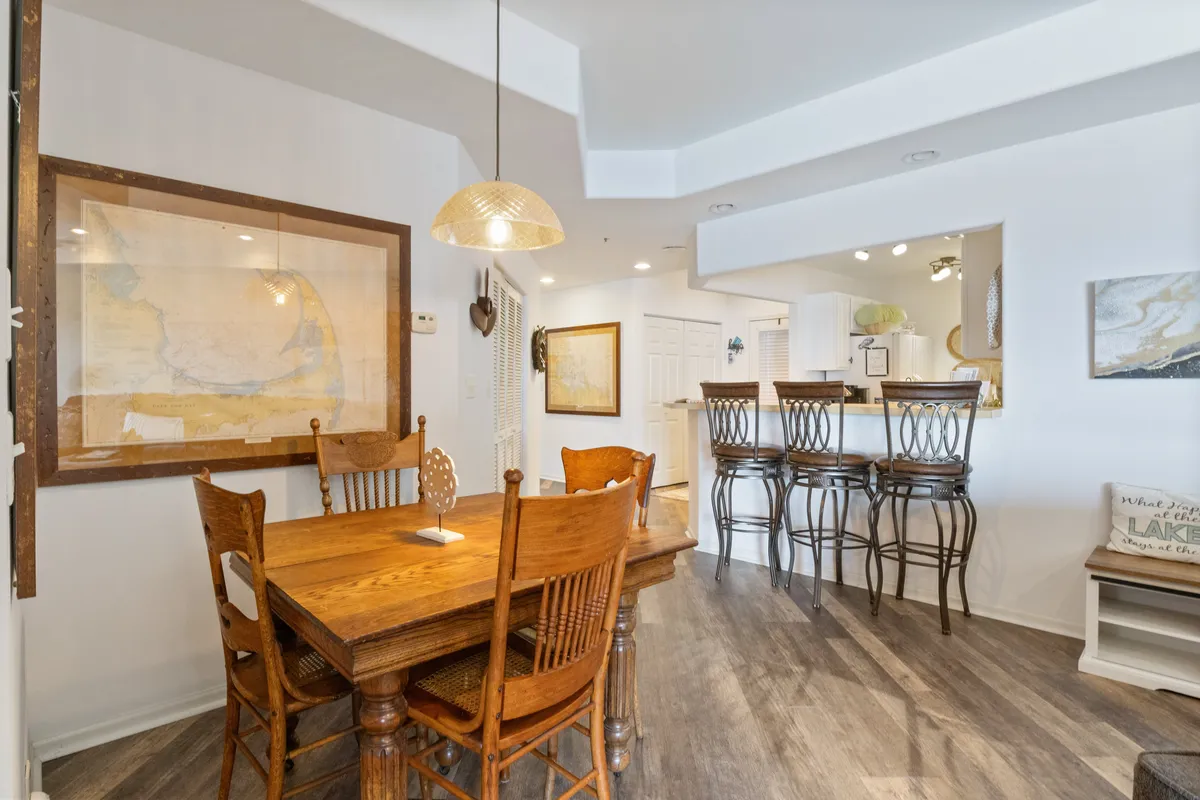 A welcoming dining area with a wooden table, bar stools, and wall art. The space is arranged for family meals, casual dining, or social gatherings, creating an atmosphere ideal for sharing food and conversation.